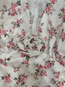 Gros plan d'une robe d'été fleurie blanche avec une décoration de rose en tissu 3D détaillée.