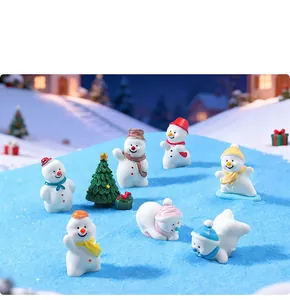 Close-up of cute miniature Christmas snowmen and trees in a winter snow landscape setting
