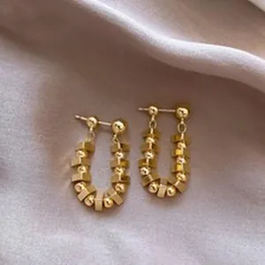 Close-up of elegant gold-plated vintage drop earrings displayed on soft silk fabric.