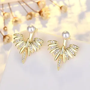 Close-up of elegant gold-plated pearl earrings with radiating crystal wing design.