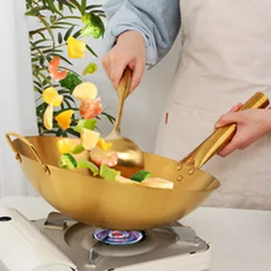 Action shot of a large gold stainless steel serving spoon in a wok