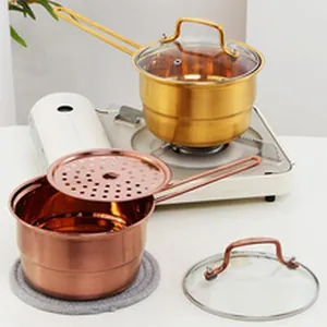 Detail of gold and copper stainless steel saucepans with glass lids and steamer