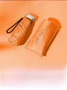 Compact orange mini sun umbrella with UPF 50 plus protection and flat folding design