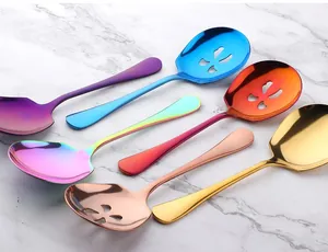 Colorful stainless steel serving and slotted spoons arranged on a marble surface