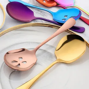High-end colorful stainless steel serving spoons and colanders on a marble table.