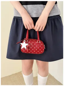 Close-up detail of red polka dot bowling handbag with white star charm accessory