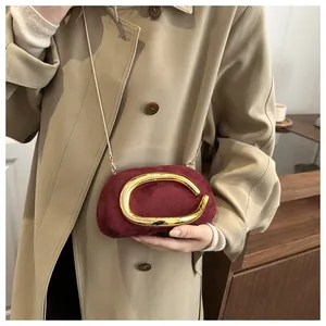 Vista dettagliata della pochette in camoscio bordeaux con decoro in metallo dorato a C