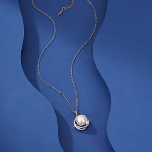 Detail view of an elegant pearl pendant necklace with sparkling accents on blue background