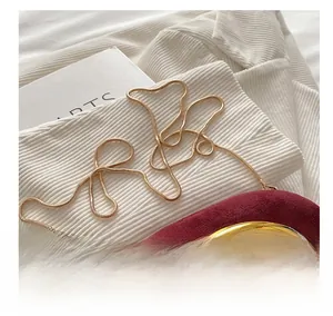 Detailaufnahme des goldenen Schlangenkettengurts an einer burgunderroten Wildleder-Clutch