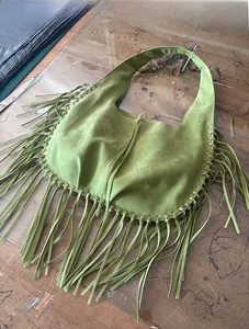 Detailed view of a green faux suede hobo bag featuring long stylish fringe details