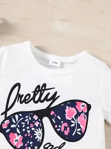 Detail of white baby t-shirt with floral sunglasses print and 3-6M size tag.
