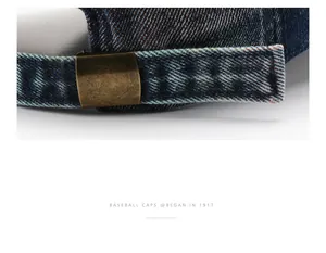 Close-up of the vintage bronze metal buckle and washed denim strap on a baseball cap