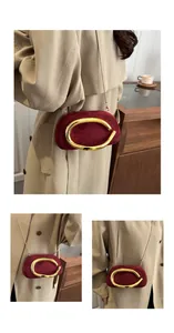 Primo piano di una borsa pochette in pelle scamosciata bordeaux con anello metallico d'oro.