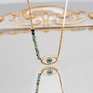 Elegant Evil Eye necklace with turquoise beads on a reflective gold mirror surface