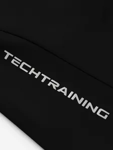Detaillierte Makroansicht des silbernen TECHTRAINING-Aufdrucks auf schwarzen Sportshorts