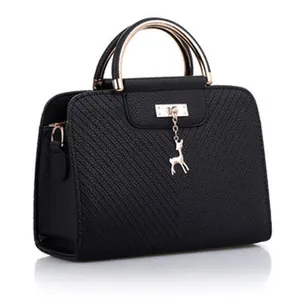 Primo piano di una borsa nera testurizzata con ciondolo a cervo dorato e manico