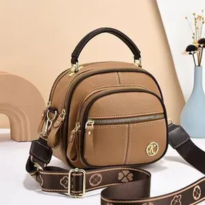 Dettaglio di borsa marrone con tracolla larga decorata con motivo a quadrifoglio
