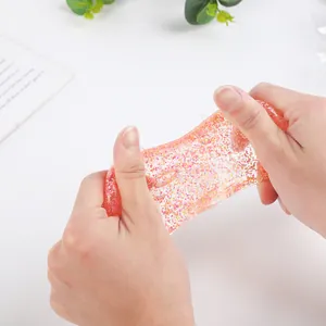 Close-up of hands stretching a transparent pink squishy toy with colorful glitter sequins