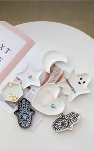 Detail view of various ceramic jewelry trays in heart, star, moon, ghost, and hamsa shapes