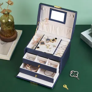 Detailed close-up showing tiered storage compartments inside a blue leather jewelry box