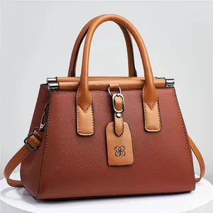 Brown lychee pattern handbag with top handles and adjustable strap on a display stand