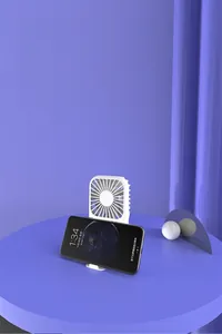 White mini portable USB fan with a functional base used as a smartphone stand