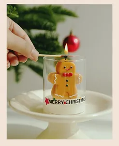Close-up of a festive gingerbread man scented candle being lit with a match in a glass jar.