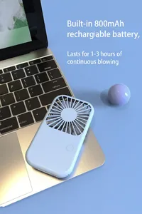 Detail view of a light blue portable mini handheld fan placed on a laptop keyboard