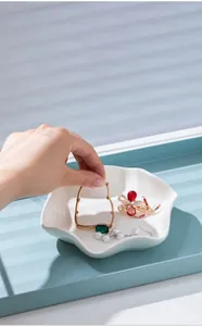 Close-up of a white ceramic flower-shaped jewelry tray holding elegant accessories.