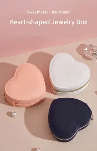 Close-up of three heart-shaped jewelry boxes in pink, white and navy blue textured leather.