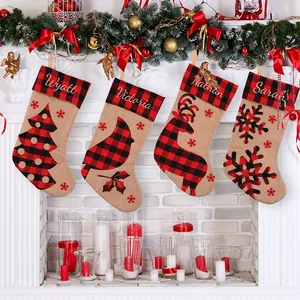 Set of four red and black buffalo plaid burlap Christmas stockings hanging on fireplace