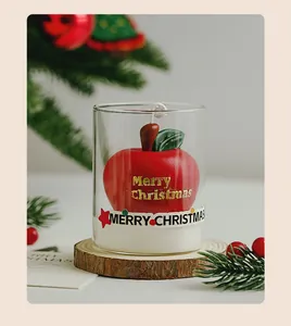 Macro detail of red apple scented candle in a clear glass cup with festive decor