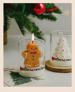 Close-up of gingerbread man and tree shaped scented candles in festive glass cups