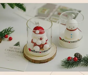 Close-up detail shot of Santa Claus and Snowman 3D scented candles in glass cups for Christmas
