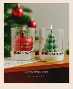 Close-up of festive Christmas tree and red apple scented candles lit in glass cups