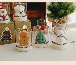 Variety of Christmas scented candles in glass cups with festive designs.