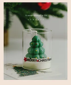 Detailed close-up of a green Christmas tree scented candle in a transparent glass jar.