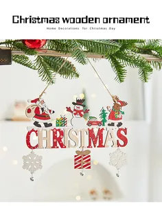 Close-up of a festive wooden Christmas ornament with Santa and snowman on a tree branch