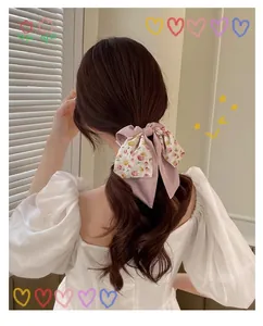 Élégant chouchou à nœud floral avec des rubans de soie roses sur la queue de cheval du modèle