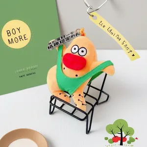 Humorous orange plush doll keychain with green bikini outfit sitting on a mini black wire chair