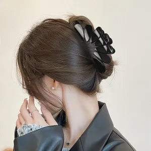 Macro detail of a large black glossy teardrop-shaped hair claw clip styled in a chic bun.