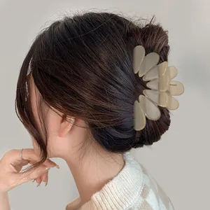 Close-up of a matte beige flower-shaped hair claw clip on a model's hair bun