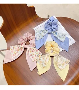 Vue détaillée de trois chouchous à nœuds fleuris avec rubans en rose, bleu et jaune.