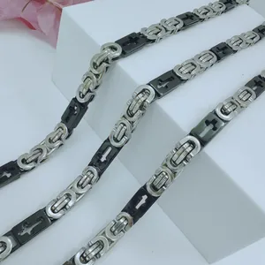 Close-up detail of stainless steel men's chain with decorative black cross pattern links