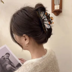 Detail view of a large tortoiseshell hair claw clip worn on a bun for thick hair.