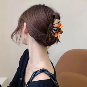 Close-up view of a large elegant amber tortoiseshell hair claw clip worn on model's hair