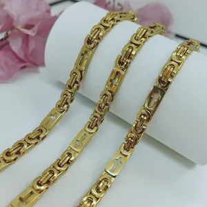 Macro view of gold stainless steel Byzantine chain necklace with cross pattern design