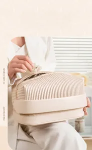 Detail of cream pleated makeup bag with double layer storage and convenient top handle