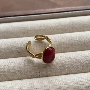 Detail of vintage gold open ring featuring a round red gemstone and leaf texture