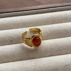 Vintage-style oval red gemstone ring with adjustable open band and gold engraving details.